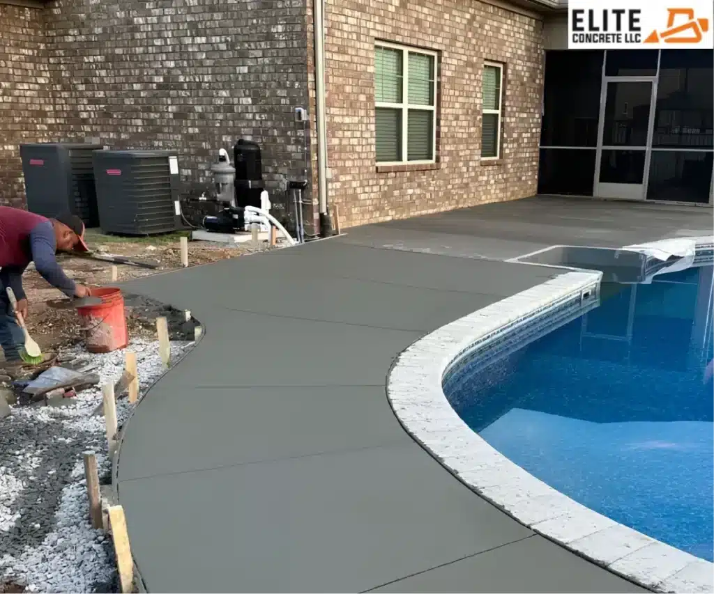 A worker using a hand trowel to smooth out the edge of a fresh concrete pool deck.